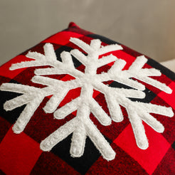 Close-up of raised embroidery on embroidered polyester canvas pillow cover with white snowflake on red buffalo plaid