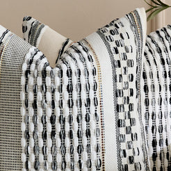 Close-up of raised loops and woven texture on chenille-textured polyester pillow cover with black stripes on cream