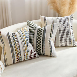 Chenille-textured polyester pillow covers with black, olive and rust striped designs, styled on a cream sofa