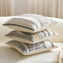 Chenille-textured polyester pillow covers with mixed neutral striped designs, stacked on a cream sofa