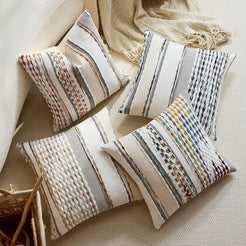 Chenille-textured polyester pillow covers with mixed neutral striped designs, arranged beside a chair