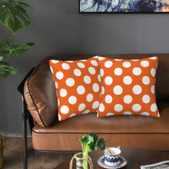 Orange polka dot velvet pillow covers styled on a sofa