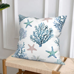 Short-pile plush polyester pillow cover with blue coral and pastel starfish print, styled on a woven chair