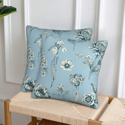 Set of two velvet pillow covers with light blue mixed floral stems, styled on a woven chair