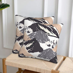 Set of two velvet pillow covers with black and beige mountains, styled on a woven chair