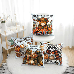 Four light blue fall pillow covers with Highland cow, pumpkin spice, harvest and raccoon designs, styled on a bench