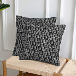 Velvet pillow covers with small gray block-print-inspired motifs, styled on a woven chair