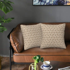 Velvet pillow covers with small taupe block-print-inspired motifs, styled on a brown leather sofa