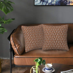 Velvet pillow covers with small rust block-print-inspired motifs, styled on a brown leather sofa