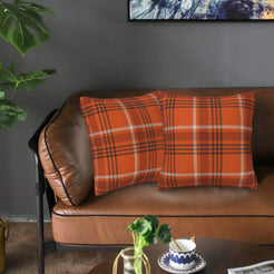Fall velvet pillow covers with bright orange windowpane plaid, styled on a brown leather sofa