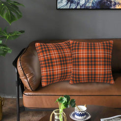 Fall velvet pillow covers with fine orange and black plaid, styled on a brown leather sofa