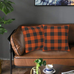 Fall velvet pillow covers with orange and black buffalo check, styled on a brown leather sofa