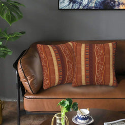 Velvet pillow covers with rust vertical geometric stripes, styled on a leather sofa