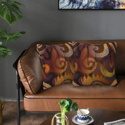 Velvet pillow covers with burgundy and orange abstract dot pattern, styled on a leather sofa
