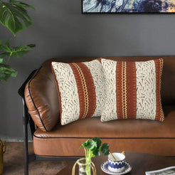 Velvet pillow covers with cream and rust central stripe pattern, styled on a leather sofa
