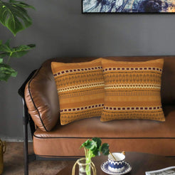 Velvet pillow covers with mustard geometric woven-style bands, styled on a leather sofa
