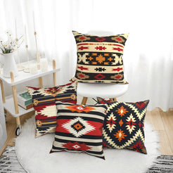 short-pile plush polyester pillow covers with black, red and cream tribal geometric prints, arranged beside a white chair