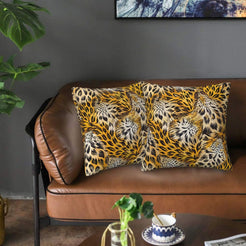 Velvet pillow covers with golden leopard spots with pale feathered accents, styled on a brown leather sofa