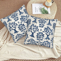 Block-print-inspired velvet pillow covers with navy folk trees and flowers, styled on a woven chair
