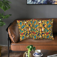 Velvet pillow covers with bright butterflies and leaves on mustard, styled on a brown leather sofa
