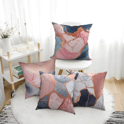 Four short-pile plush pillow covers with navy, blush and gray marble designs, styled in a bright room
