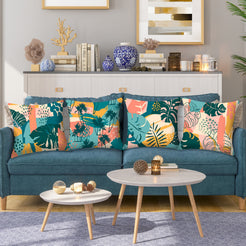 Short-pile plush pillow covers with coral, teal and mustard tropical leaves, styled on a teal sofa