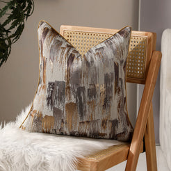 Brown and gold abstract jacquard pillow covers styled on a chair