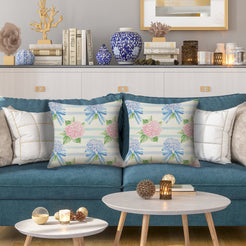 Water-resistant linen-look polyester pillow covers with hydrangeas and bows on horizontal stripes, styled on a blue sofa