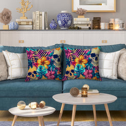 Water-resistant pillow covers with gold skulls, hibiscus and teal leaves, styled on a blue sofa
