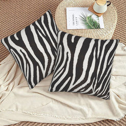 Velvet pillow covers with black and white narrow zebra stripes, styled on a beige sofa