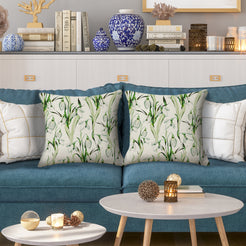 Outdoor water-resistant linen-look polyester pillow covers with green tropical leaves, styled on a blue sofa