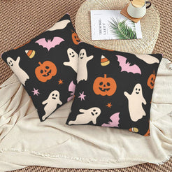 Halloween pillow covers with black ghosts, pumpkins and bats, styled on a woven chair