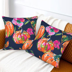 Set of two velvet pillow covers with navy pumpkins and vivid pink flowers, styled on a sofa