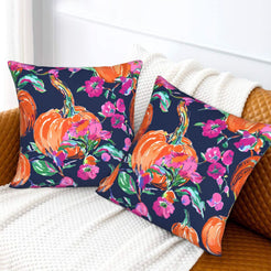 Set of two velvet pillow covers with navy pumpkin and pink floral pattern, styled on a sofa