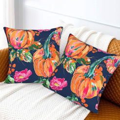 Set of two velvet pillow covers with navy pumpkins and pink roses, styled on a sofa
