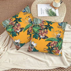 Tropical velvet pillow covers with mustard tropical birds and monstera leaves, styled on a woven chair