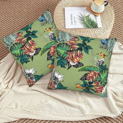 Tropical velvet pillow covers with sage tropical birds and monstera leaves, styled on a woven chair