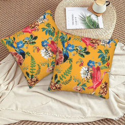 Tropical velvet pillow covers with mustard parrots and flowers, styled on a woven chair