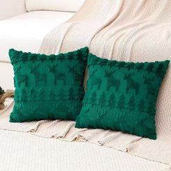 Quilted polyester pillow covers with subtle woven reindeer on emerald green, styled on a cream sofa