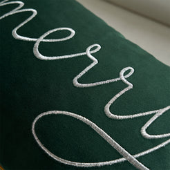 Close-up of white embroidered Merry script on green velvet
