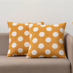 Loop-pile textured polyester pillow covers with raised white polka dots on mustard yellow, styled on a neutral sofa