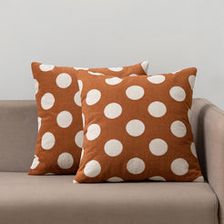 Loop-pile textured polyester pillow covers with raised white polka dots on rust brown, styled on a neutral sofa