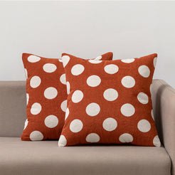 Loop-pile textured polyester pillow covers with raised white polka dots on brick red, styled on a neutral sofa