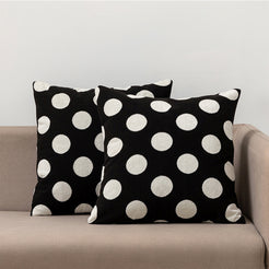 Loop-pile textured polyester pillow covers with raised white polka dots on black, styled on a neutral sofa