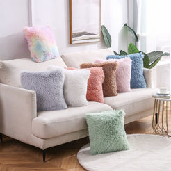 Faux-fur plush polyester pillow covers with gray, pink, brown, white and blue long-pile covers, styled on a cream sofa