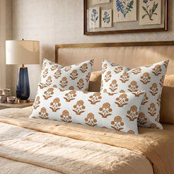 Long lumbar pillow cover with rust block-print-inspired floral sprigs, arranged with square covers on a bed