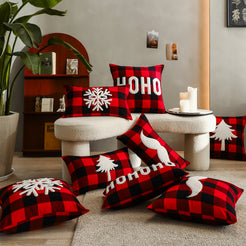 Red plaid embroidered polyester canvas pillow covers with white snowflake, pine tree and HO HO HO motifs in a living room