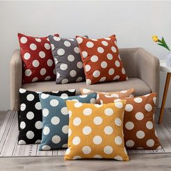 Loop-pile textured polyester pillow covers with raised white polka dots in assorted colors, grouped on a neutral sofa