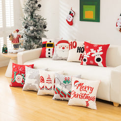 embroidered polyester canvas pillow covers with assorted red and cream Christmas embroidery, displayed around a white sofa
