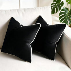 Velvet pillow covers with black velvet with white piping, styled on a cream chair